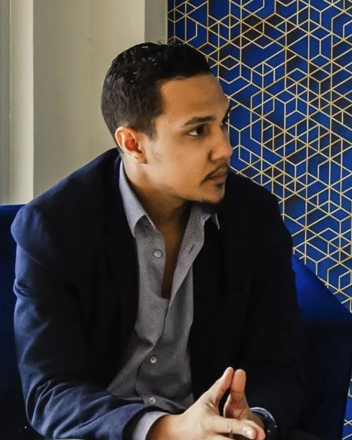Luis Arvelo, seated, in a navy blazer.